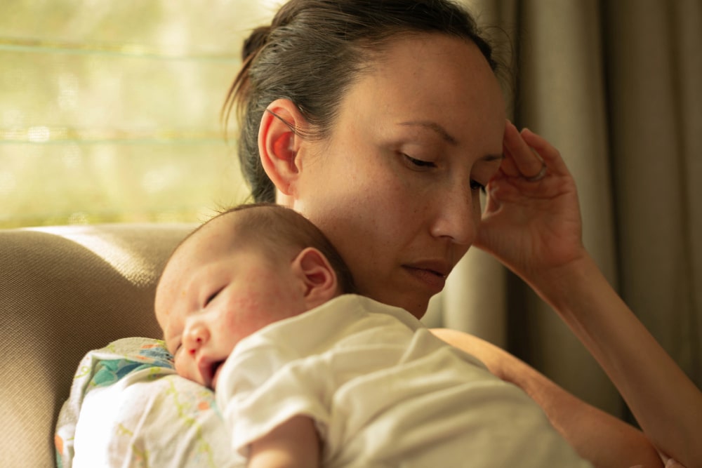 Post natal depression A unhappy mother suffering from postpartum depression, holding her baby.