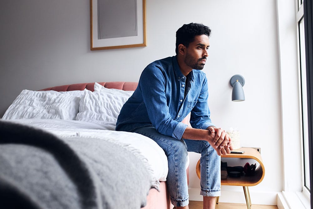 Man sat on bed feeling anxious