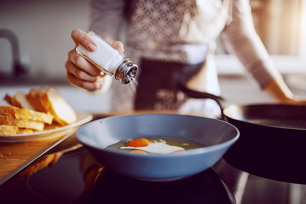 Person shaking salt on food