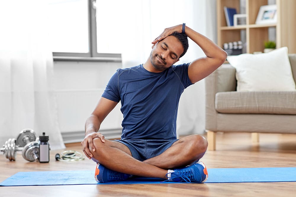 Person sitting on floor at home doing some stretches to help relieve stress
