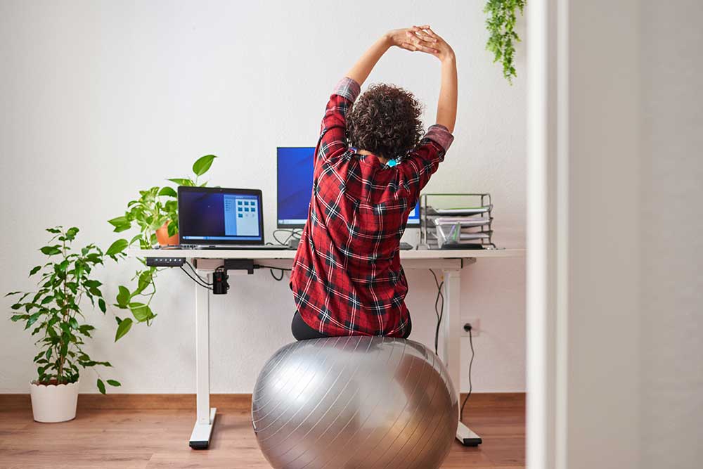 Supporting-physical-health-of-staff-06.26 Employee doing some stretches on work break at desk